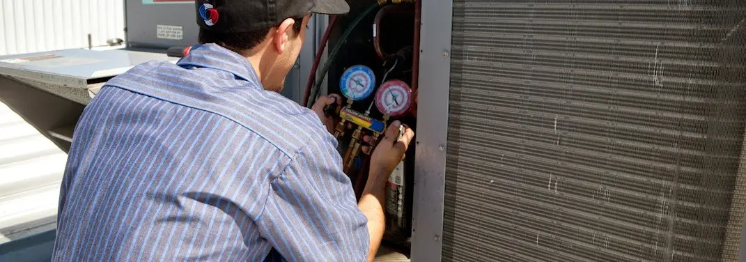 HVAC technician servicing a condenser unit in Brownville